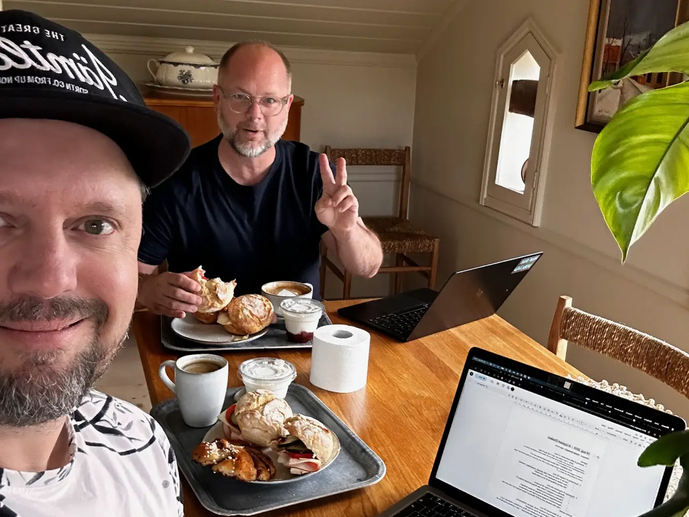 Fredrik och Jens arbetar tillsammans med Challero vid ett bord med datorer och arbetsmaterial.